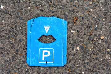 an old blue parking disc on a street