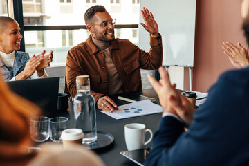 Businesspeople applauding their colleague in a boardroom