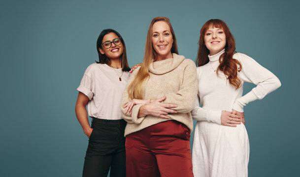 Three smiling women looking at the camera in a studio