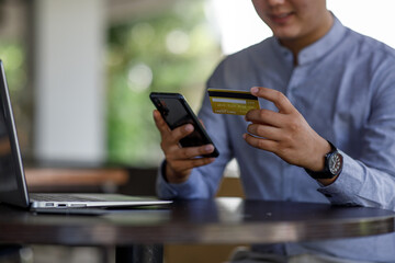 Close uo of man holding credit card and using laptop making payment online. Businesswoman or entrepreneur working at home. Online shopping, e-commerce, banking, internet store, spending money concept