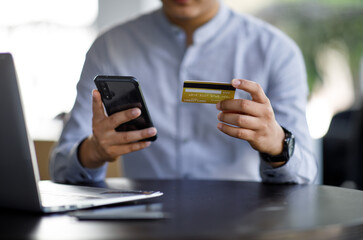 Close uo of man holding credit card and using laptop making payment online. Businesswoman or entrepreneur working at home. Online shopping, e-commerce, banking, internet store, spending money concept