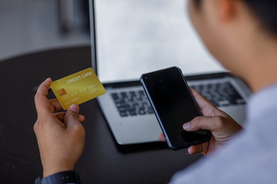 Close uo of man holding credit card and using laptop making payment online. Businesswoman or entrepreneur working at home. Online shopping, e-commerce, banking, internet store, spending money concept