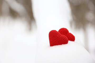 Love hearts, Valentine's card, two red knitted symbols of passion in the snow forest. Background...