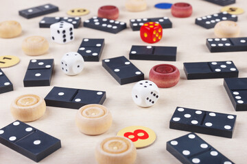 Dice, chips, dominoes and wooden checkers for board games on table close up.