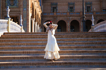 Obraz premium Flamenco dancer, woman, brunette and beautiful typical spanish dancer is dancing and clapping her hands on the stairs of a square in seville. Flamenco concept of cultural heritage of humanity.