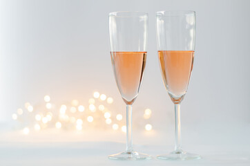 Glasses of sparkling Rose wine on white background with bokeh light for anniversary and Valentine's day concept.