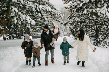 Fototapeta na wymiar Big happy family spending time outdoors on snowy winter day, walking in a park.
