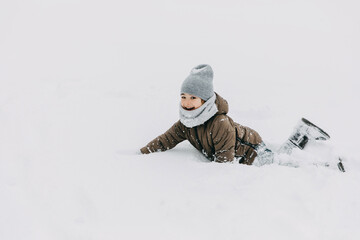 Fototapeta na wymiar Little boy playing in snow on cold winter day, laughing, having fun.