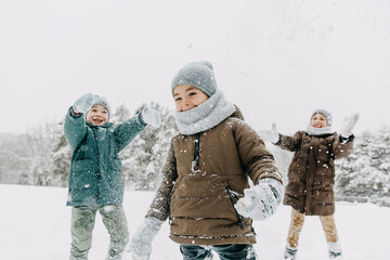 Children playing outdoors on a snowy winter day in a forest, laughing, having fun.