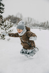Fototapeta na wymiar Boy playing on winter day, jumping in deep snow in mountains.