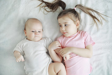 Children lie on the bed next to the newborn baby, little sister.