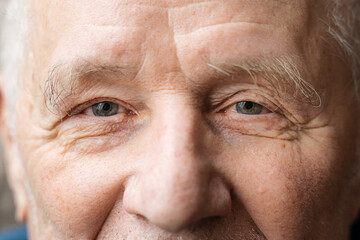 Close up portrait of old smiling man looking at camera. He is open-eyed and cheerful. Smiling blue...
