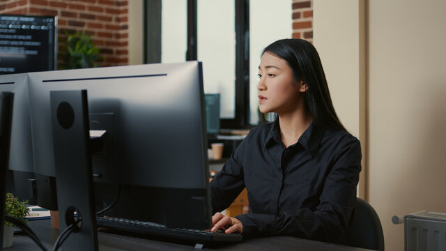 Portrait of asian programer focused on writing code sitting at desk in software development office. System engineer concentrating on creating algorithm for it startup company.