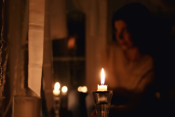 girl at the window dreams in winter evening / the romance of candle, the beautiful model in Christmas evening dreams