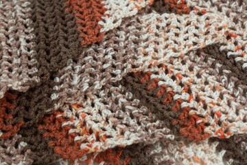 Close up colorful yarn texture background, light beige, dark brown, orange red strains. Shallow depth of focus. Knitting and crochet, craft work concept. Winter clothes. Color combination for styling.