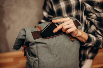 Young woman put smart phone into canvas bag