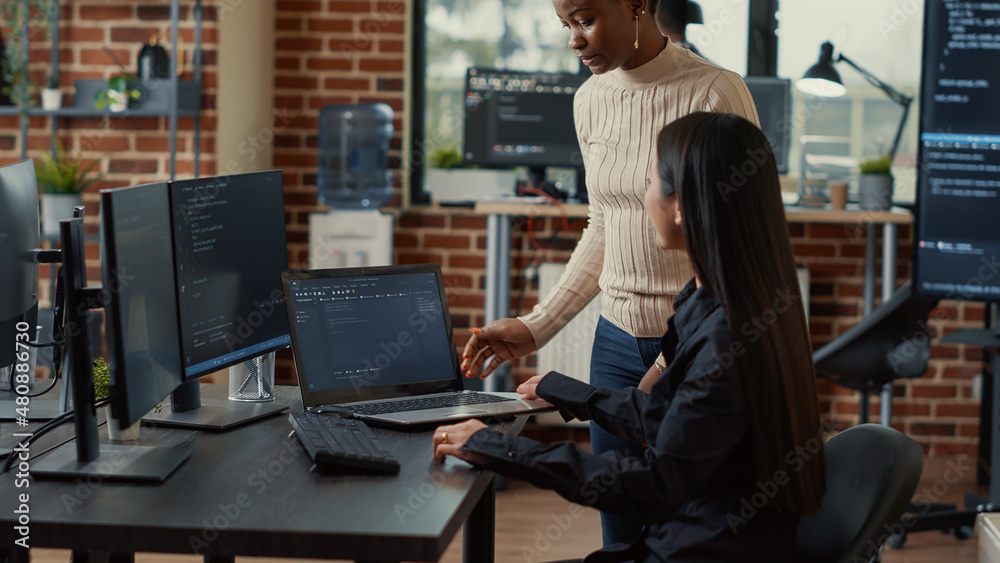 Poster coder holding laptop with coding interface entering software development agency office sitting down 