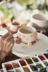 a woman potter painting a cup in her crafts workshop. .