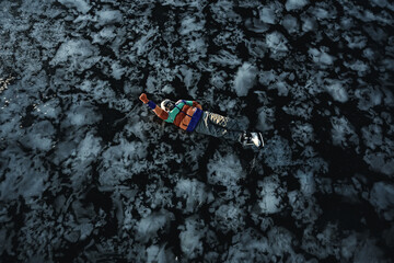 a man in ice skates lies on the transparent ice of the lake, view from above, aerial photography