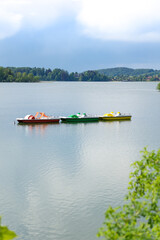 Drei farbige Tretbote auf einem stillen See