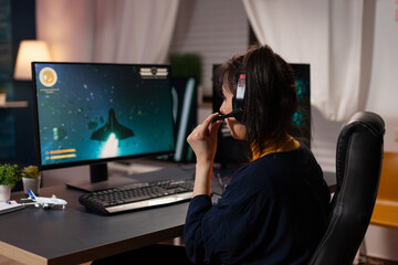 Person using headset to stream online video games on computer. Gamer live streaming gameplay with headphones and monitor. Player broadcasting game in cyberspace with modern equipment.