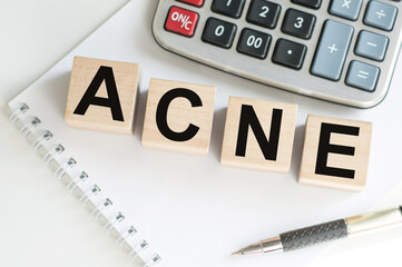 Medicine concept. ACNE word on wooden cubes on a table next to a notebook, calculator and pen
