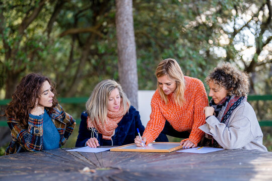 Friends looking at woman writing on whiteboard sitting in park