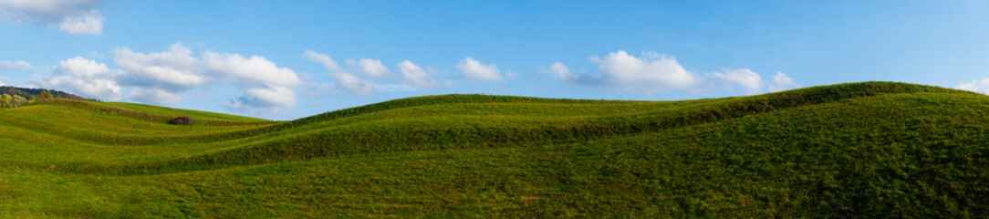 Scenic fields of grass under a blue sky. Summer in a highland countryside.