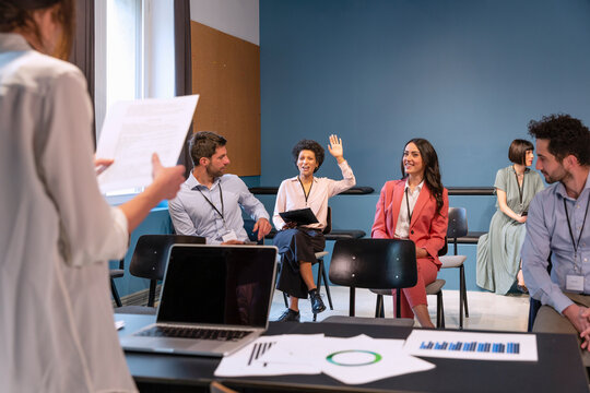 Businesswoman raising hand in meeting at office