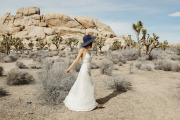Woman in boho style dress and hat dancing in the Joshua Tree desert