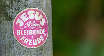 Verwitterter farbiger Aufkleber an einem Metallpfosten