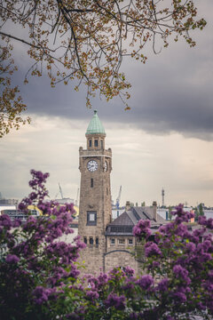 Germany, Hamburg, Clock tower in Saint Pauli Piers with blooming flowers in foreground