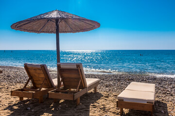 Empty deck chairs on coastal beach with clear line of horizon over sea in background