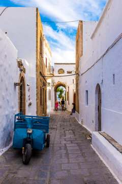 Blue motorized tricycle in whitewashed alley