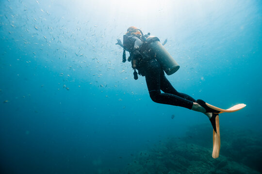 Woman swimming undersea below school of fish at Del Coco beach