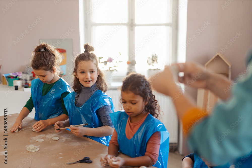 Wall mural Group of little kids working with pottery clay during creative art and craft class at school.