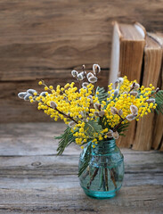 Spring bouquet of fluffy Mimosa flowers and willow buds on wooden background. symbol of 8 March, world women's day. festive spring season concept.