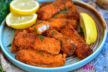 Fototapeta premium Close up of Crispy breaded deep fried fish fingers with breadcrumbs served with remoulade sauce and lemon Cod Fish Nuggets on rustic wood table background