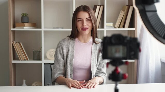 Female blogger. Video record. Self presentation. Happy inspired woman shooting on photo camera sitting in light room interior.