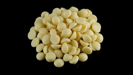 White chocolate chips on black background. Chocolate callets. Confectionery concept