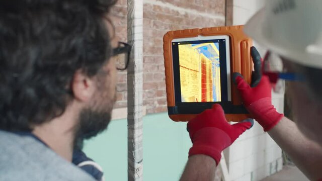 Businessman and foreman check heating with infrared camera on tablet. Realtime