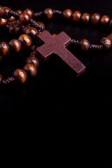 Close-up of wooden Christian cross on black background and copyspace