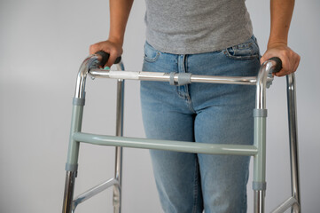 A woman is walking with a walker on a white background