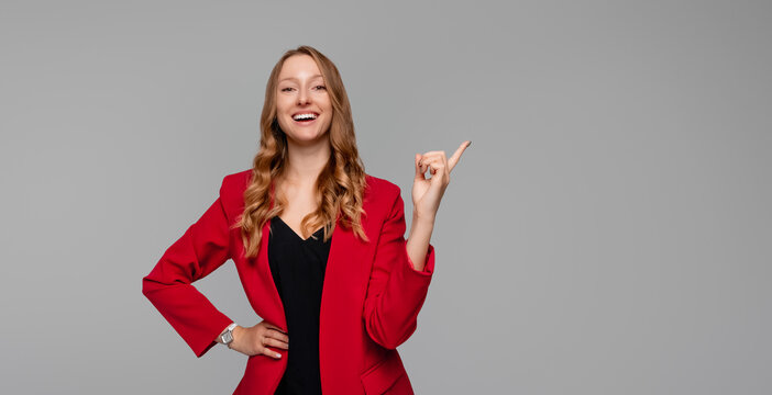 I have great idea. Smart attractive female office manager in stylish clothes, raising index finger in eureka gesture, making suggestion with satisfied smile, gray background