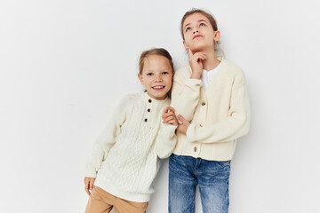 two little girls in sweaters posing childhood light background