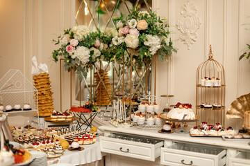 Exquisitely decorated sweet buffet at wedding banquet. Varied buffet. Organization of banquets and weddings. Sweet desserts. Exquisite wedding treats. Wedding decoration.