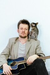 man with a guitar, a kitten is sitting on his shoulder.