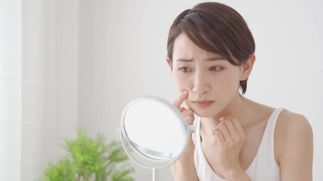 鏡を見て肌を気にする女性