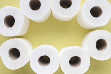 Fresh new white toilet paper rolls on yellow background. Personal hygiene and health issues concept. Top view, copy space