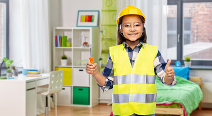 building, construction and profession concept - smiling little girl in protective helmet and safety vest with screwdriver over children's room at home background